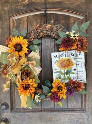 Decorative grapevine wreath with sunflowers and autumn leaves on a wooden door