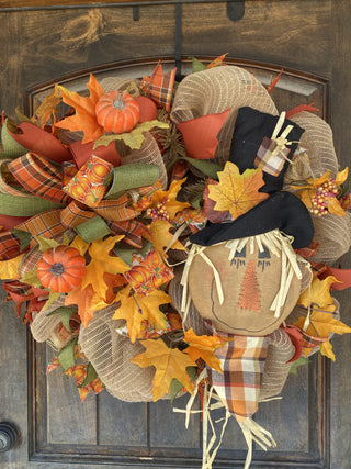 Decorative wreath with autumn elements including pumpkins, leaves, and a scarecrow.