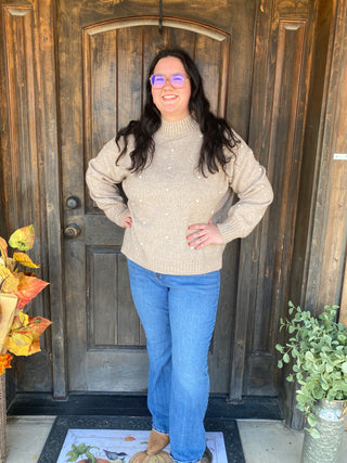 Beige turtleneck sweater with white pom poms 