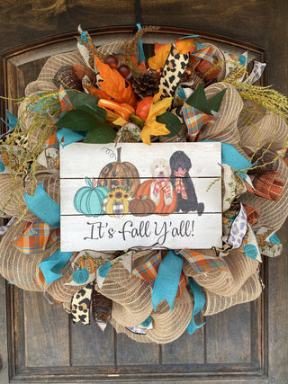 Decorative wreath with fall-themed elements and a sign saying 'It's Fall Y'all' 