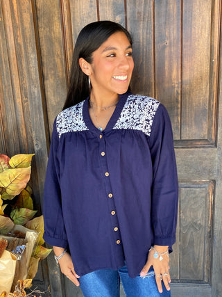 A navy-blue long sleeve blouse with white embroidery