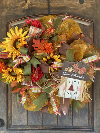 Autumn-themed wreath with sunflowers, leaves, and a scarecrow decoration 