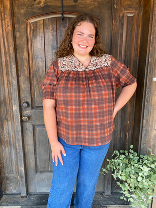 Plaid rust top with white embroidery and cuffed sleeves