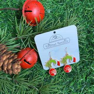 Dangle earrings of green man hand holding an ornament that says 'Merry Christmas'