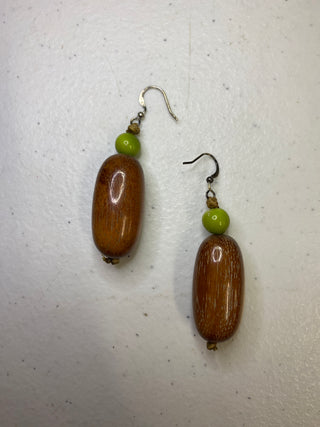 Pair of wooden oval earrings with green beads on a white background