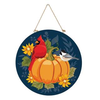 Decorative circular piece with a cardinal, pumpkin, and chickadee on a blue background