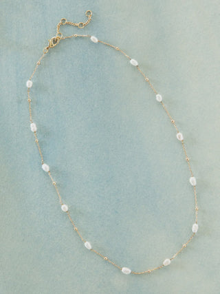 Pearl necklace with gold chain on a light blue background