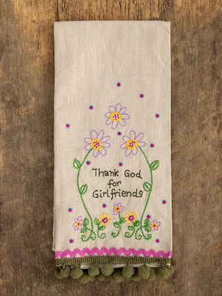Embroidered towel with floral design and text on a wooden surface