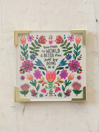 Framed artwork magnet with floral design and motivational quote on a textured wall.