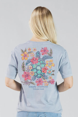 Person wearing a light blue t-shirt with a turtle and floral design, labeled 'Simply Southern Collection'.