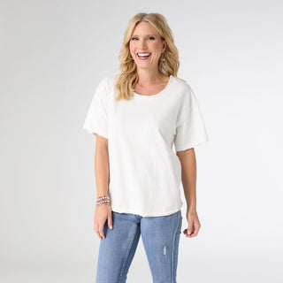 Woman wearing a white t-shirt and blue jeans on a plain background