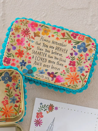 Decorative prayer box with floral design and motivational quote on a beige background