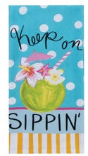 Towel with a colorful design featuring a drink and flowers on a blue background with white polka dots.