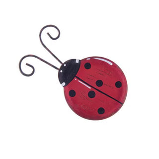 Red ladybug-shaped magnet with black spots on a white background