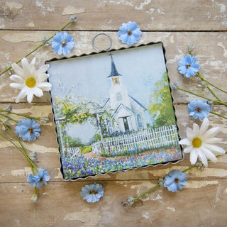 Decorative plaque with a church design on a wooden surface with flowers