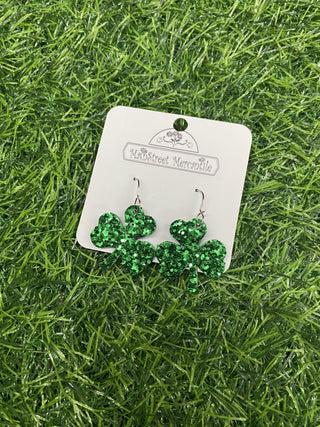 Green shamrock earrings on a card with a grass background