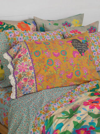 Floral patterned pillows and bedding on a bed with a white background