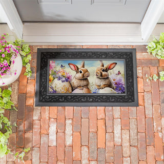 Decorative doormat with two rabbits and flowers on a brick patio