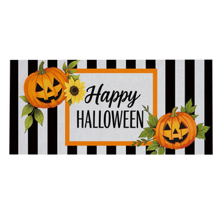 Halloween banner decoration with black and white vertical stripes, featuring two orange jack-o'-lanterns, a sunflower, green leaves, and the words 'Happy HALLOWEEN' in black script and block lettering inside an orange border.