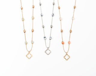 Three necklaces with clover-shaped pendants on a white background
