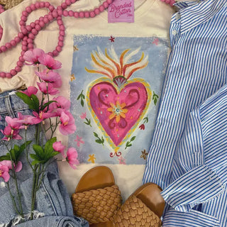 Heart-shaped painting with pink flowers, denim jeans, and a striped shirt on a textured surface.