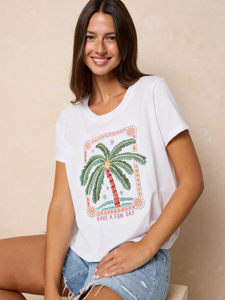 Woman wearing a white t-shirt with a palm tree design and text on a beige background