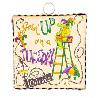 Decorative sign with a cartoon alligator, text, and Mardi Gras elements