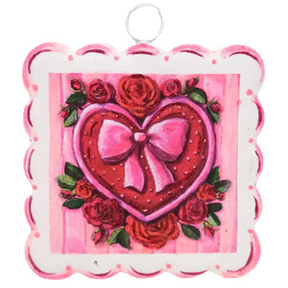 Decorative heart-shaped ornament with a pink bow and red roses on a pink background.