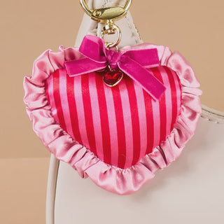 Heart-shaped keychain with pink stripes and ruffles on a beige background