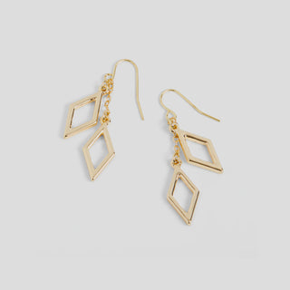 Gold geometric earrings on a light gray background