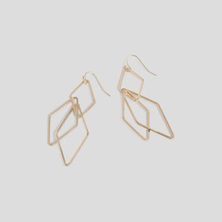 Gold geometric earrings on a light gray background