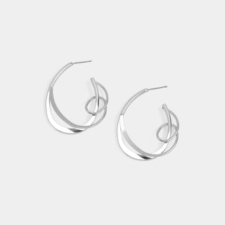 A pair of silver-toned geometric hoop earrings with overlapping curved bands and a central loop detail, shown on a light gray background.