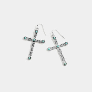 A pair of silver cross dangle earrings with small turquoise-colored stone accents, displayed on a light gray background.