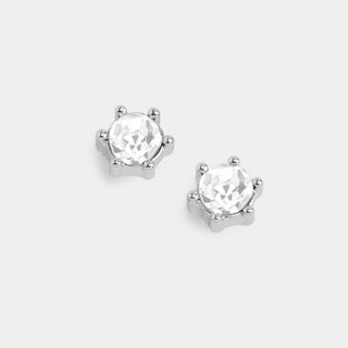 A pair of silver stud earrings with round clear faceted gemstones in a prong setting, shown on a light gray background.
