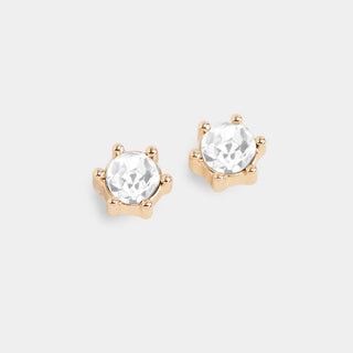 A pair of round-cut clear gemstone stud earrings in a gold prong setting, displayed on a light gray background.