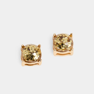 A pair of cushion-shaped stud earrings with a clear dome filled with chunky gold glitter, set in a rose gold-tone four-prong metal frame, shown on a light grey background.