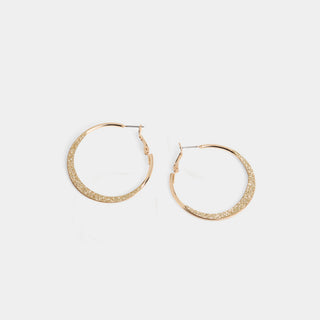 A pair of large round hoop earrings with a smooth silver polished inner frame and a wide glitter-textured front face, shown with a latch-back post closure.