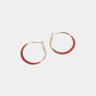 A pair of large round hoop earrings with a smooth silver polished inner frame and a wide glitter-textured front face, shown with a latch-back post closure.