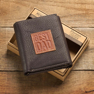 Brown leather wallet with 'Best Dad' patch on a wooden surface