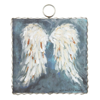 Painted angel wings on a textured blue background with a metal ring for hanging.