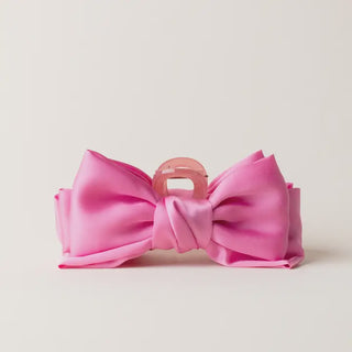 Pink bow with a clear clip on a light gray background