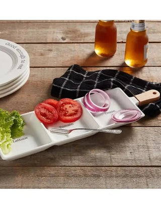White plate serveware set with hamburger ingredients lettuce, tomato, onion sections and a wooden handle