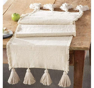 White table runner with tassels on a wooden table