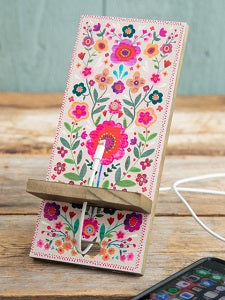 Floral phone stand on a wooden surface with a smartphone on it